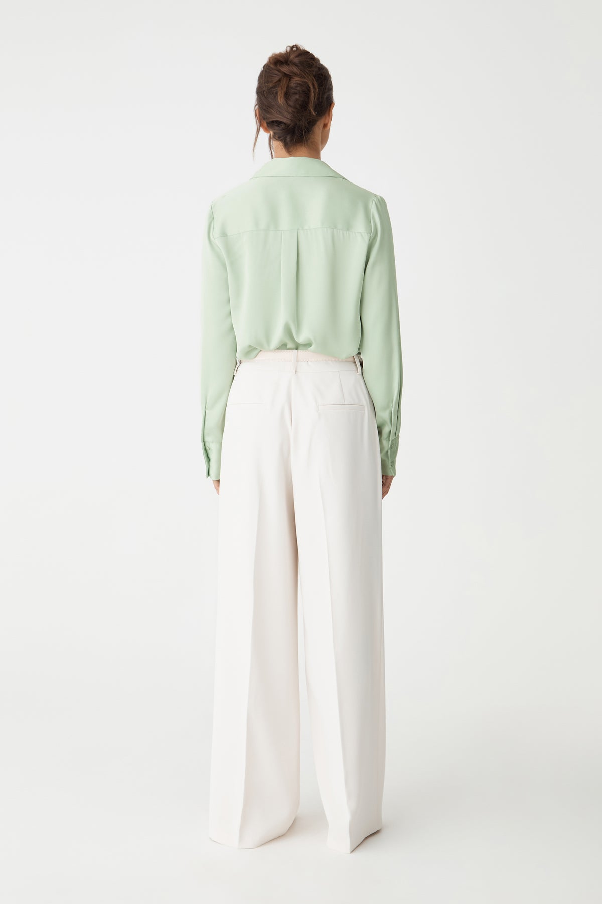 Back view of the Mae Satin Shirt in mint with cream wide-leg trousers