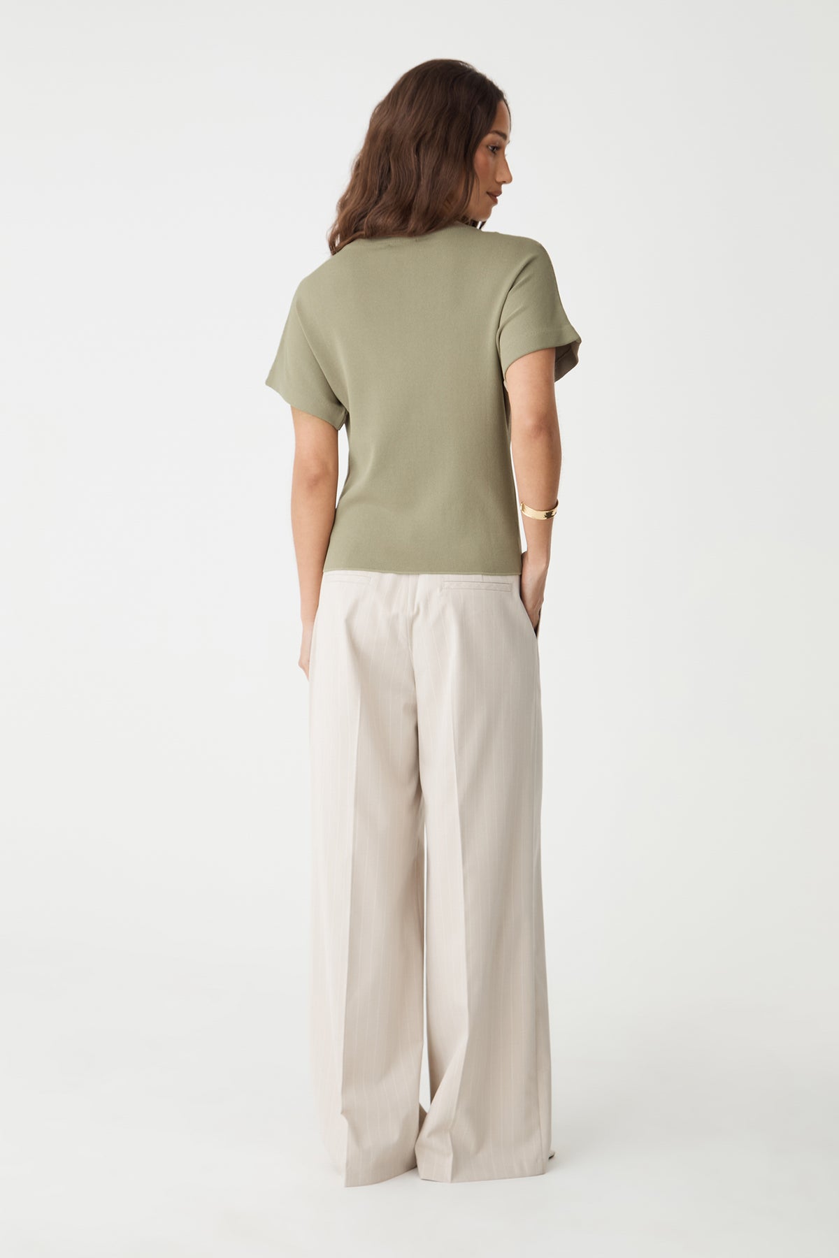 Back view of the soft khaki knit top with cream wide-leg trousers