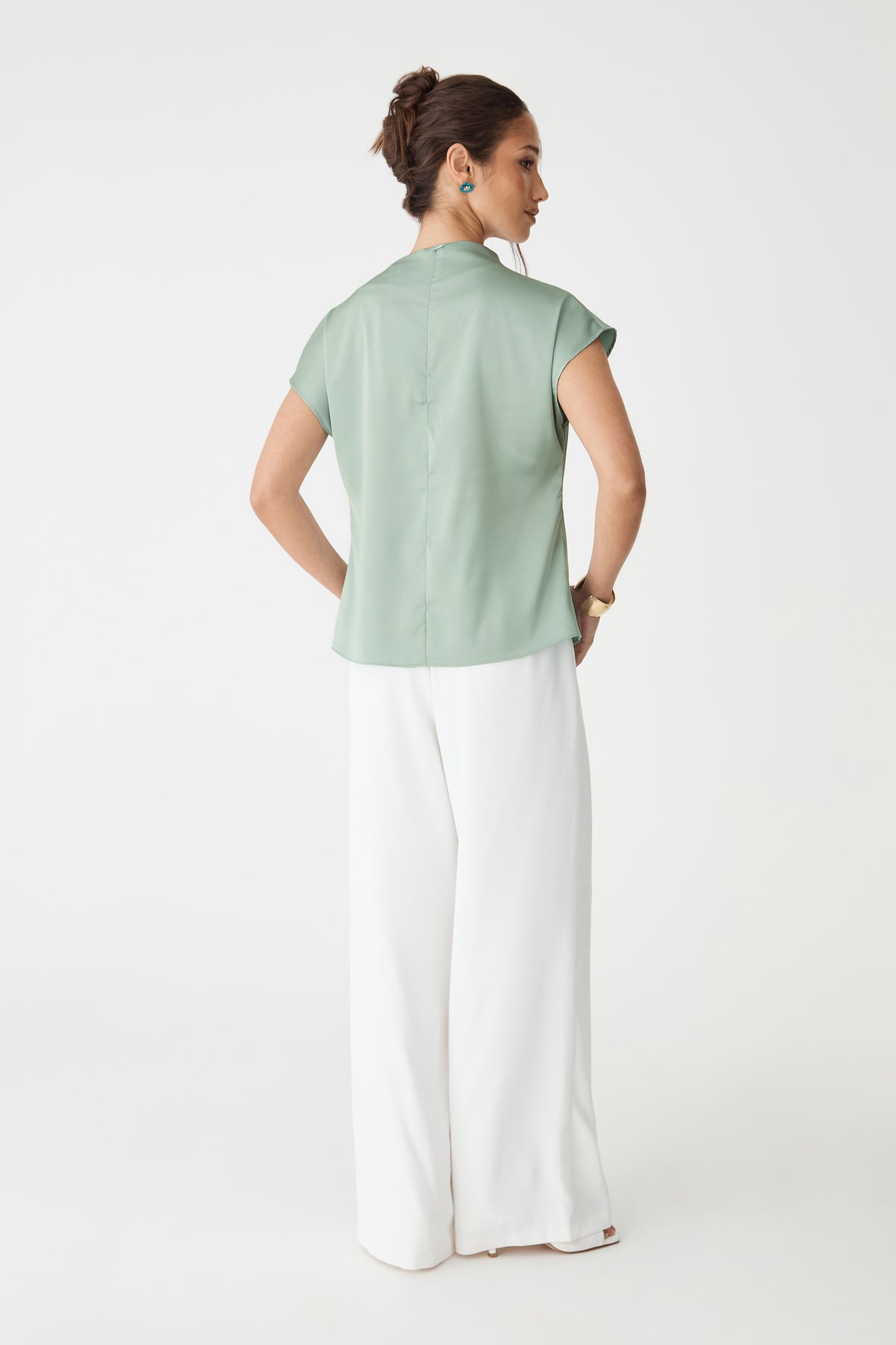 Back view of the spearmint Zafina Pleated Draped Top with white wide-leg trousers