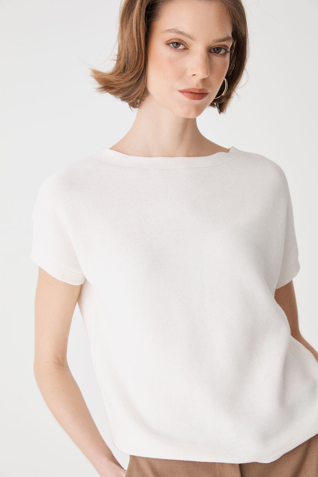 Close front view of the ivory knit top showing ribbed neckline trim and textured knit