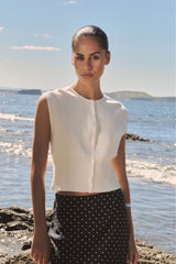 Faye Sleeveless Button Up Knit in ivory, front view worn with a black spot-print skirt
