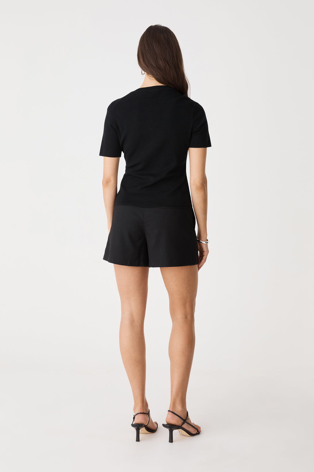 Back view of the black Mel Short Sleeve Scallop Knit worn with black shorts