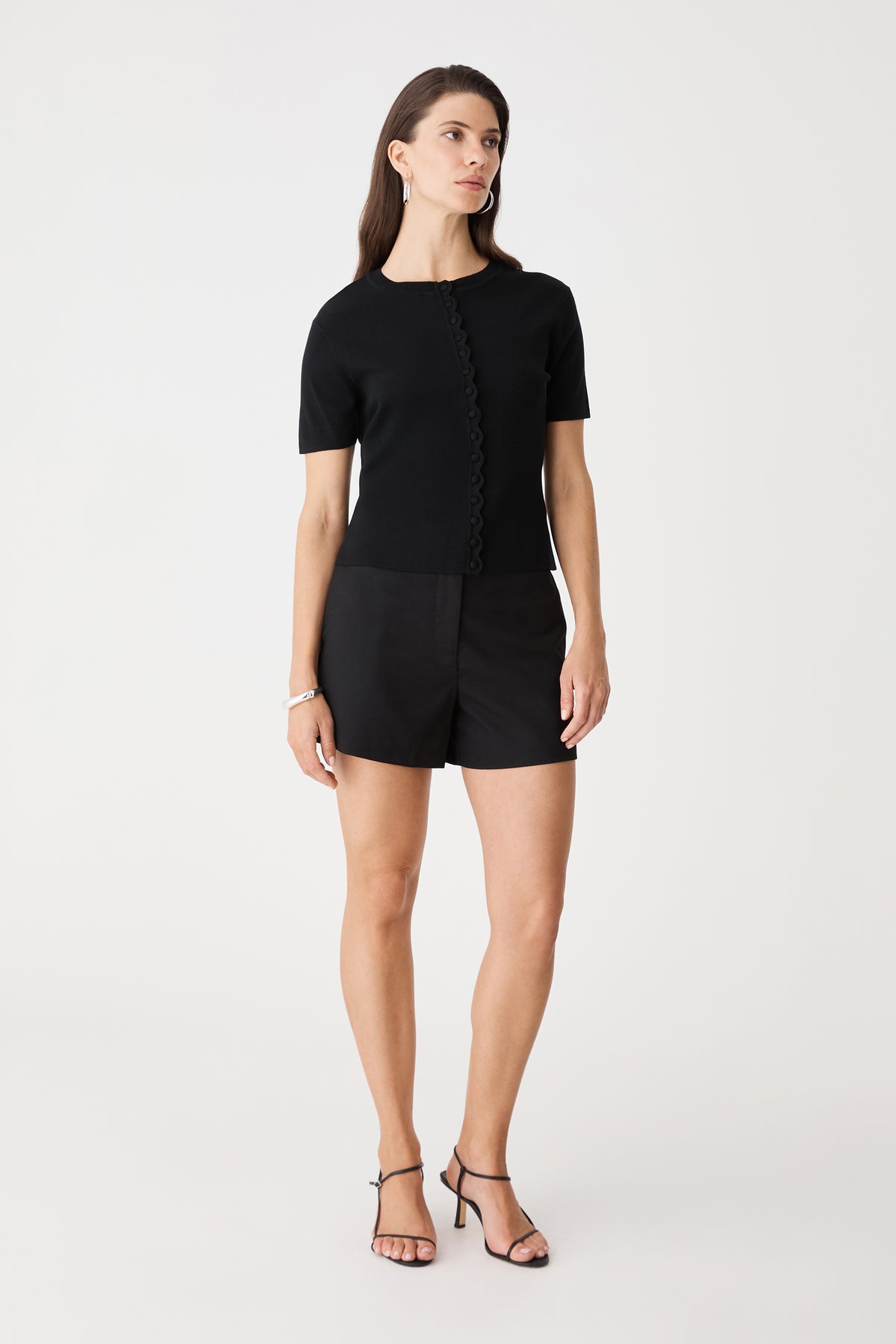 Full-length front view of the black Mel Short Sleeve Scallop Knit with black shorts and heeled sandals