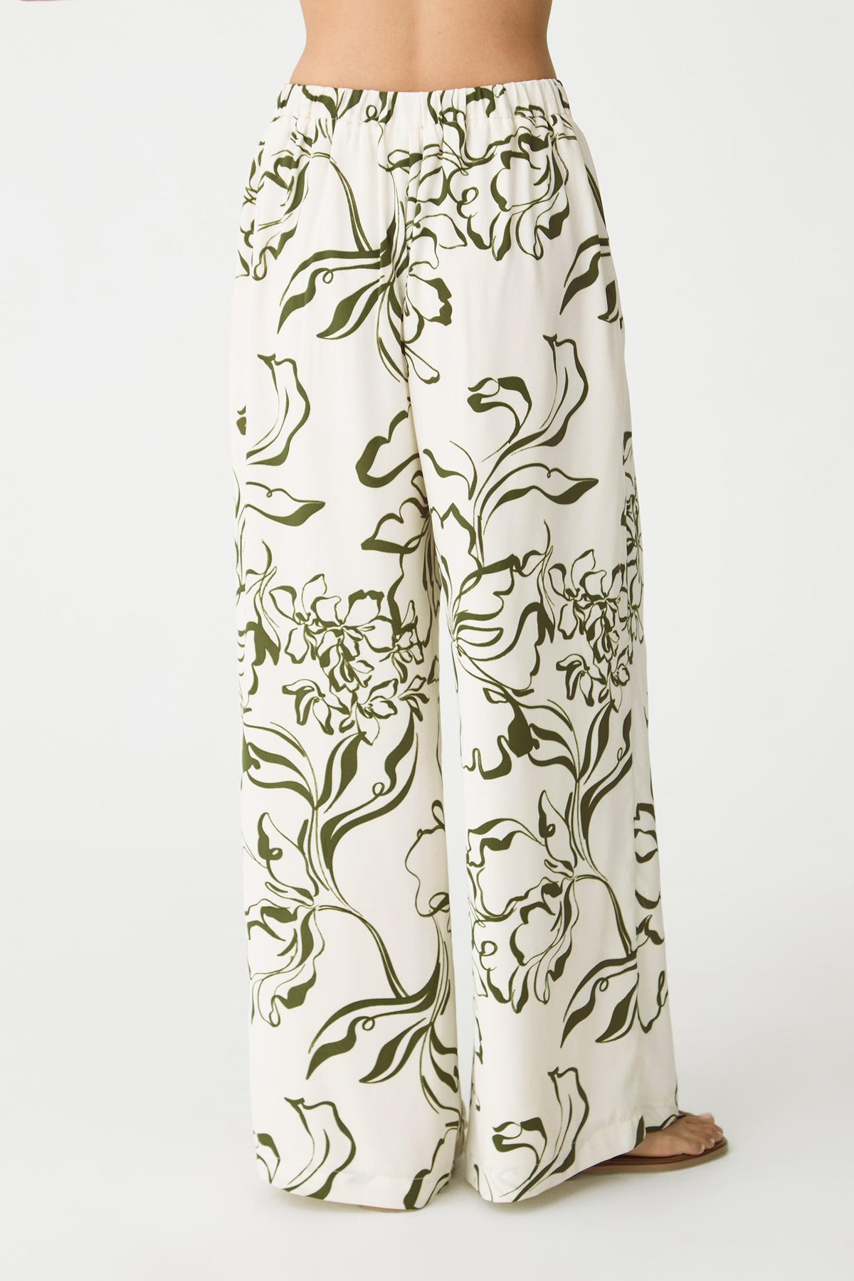 Back view showing the elasticated back waistband of the cream and olive floral wide-leg pants