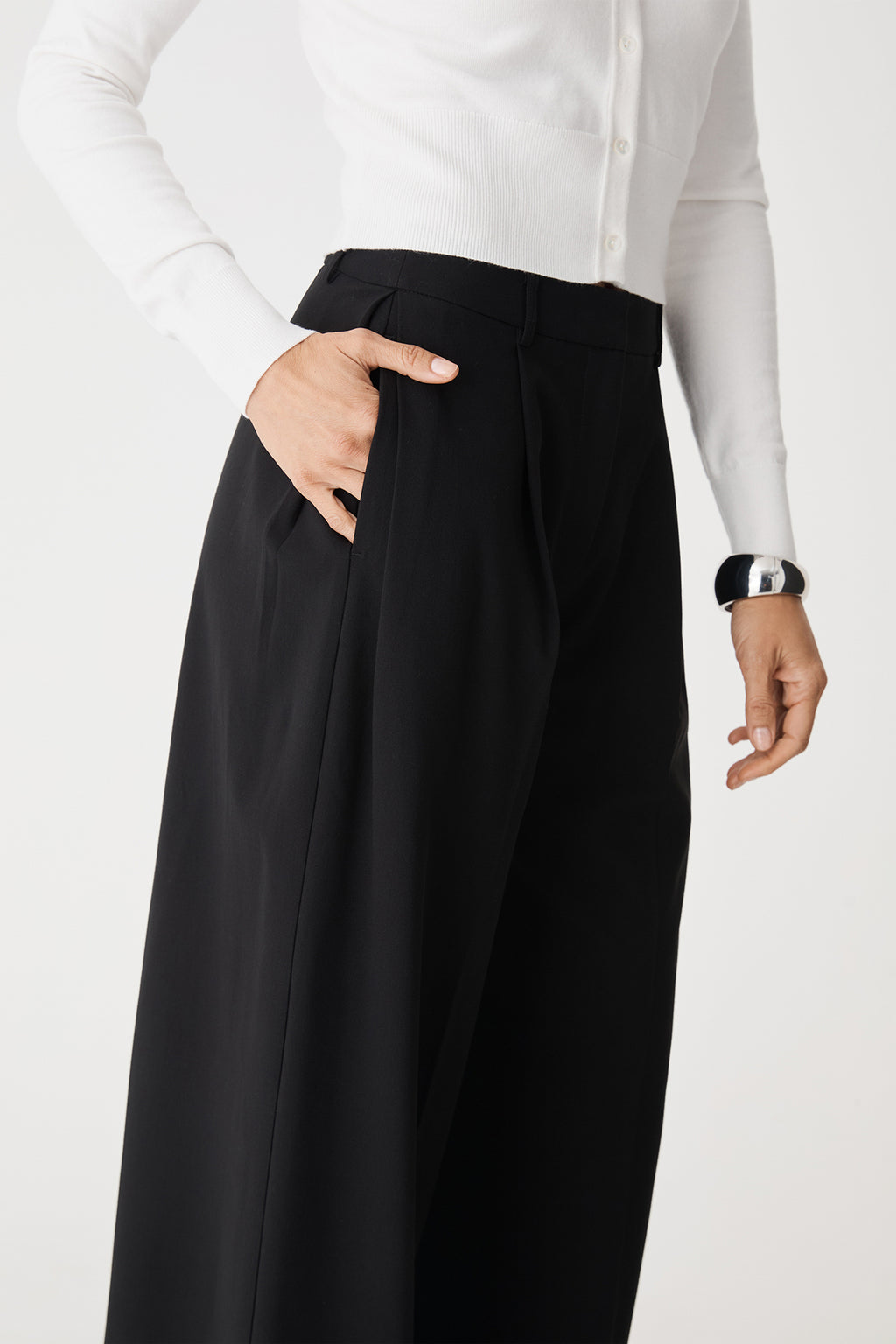 Close-up of side pocket and pleats with hand in pocket