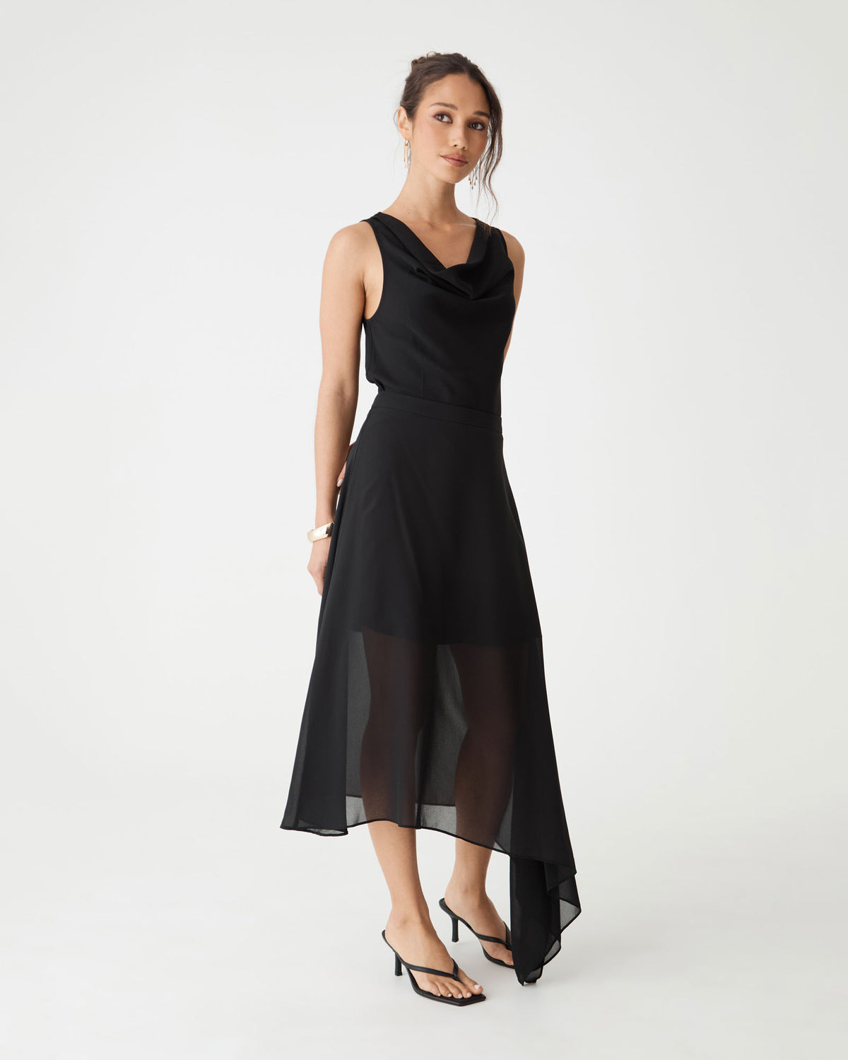 Side view of the Desiree Asymmetric Skirt in black with flowing sheer overlay