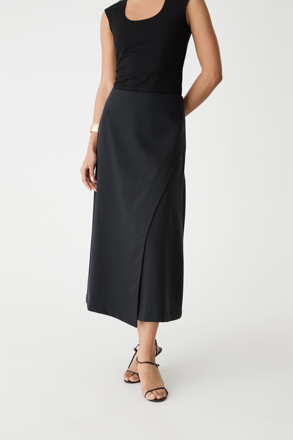 Close-up of the asymmetrical faux-wrap front and waistband of the black midi skirt