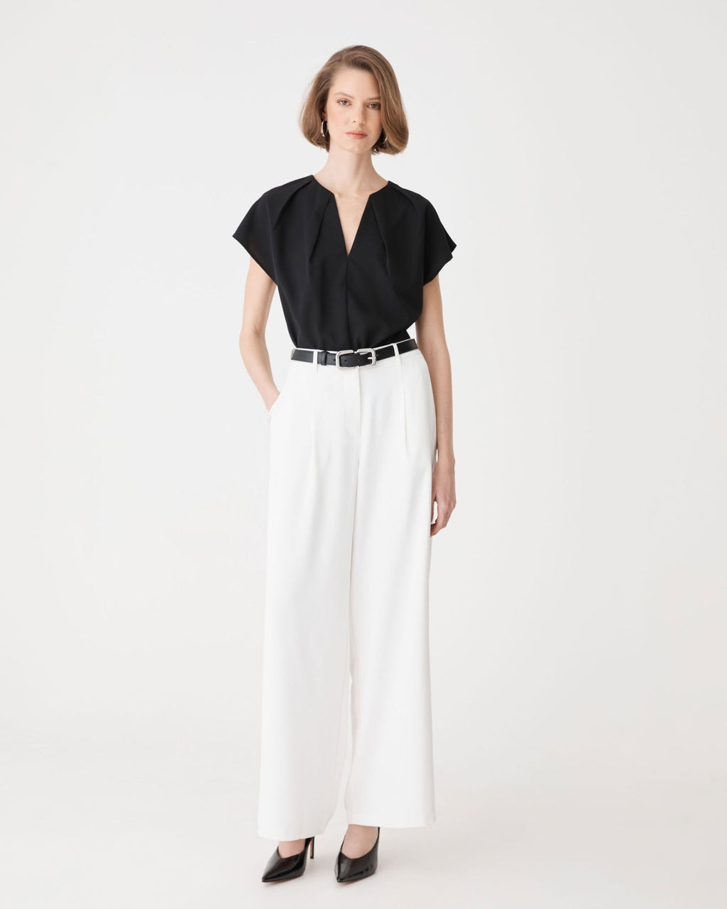 Jane Pleated Neck Top in black, front view worn with white wide-leg trousers and belt