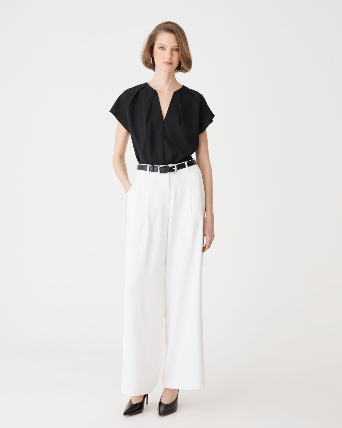 Jane Pleated Neck Top in black, front view worn with white wide-leg trousers and belt
