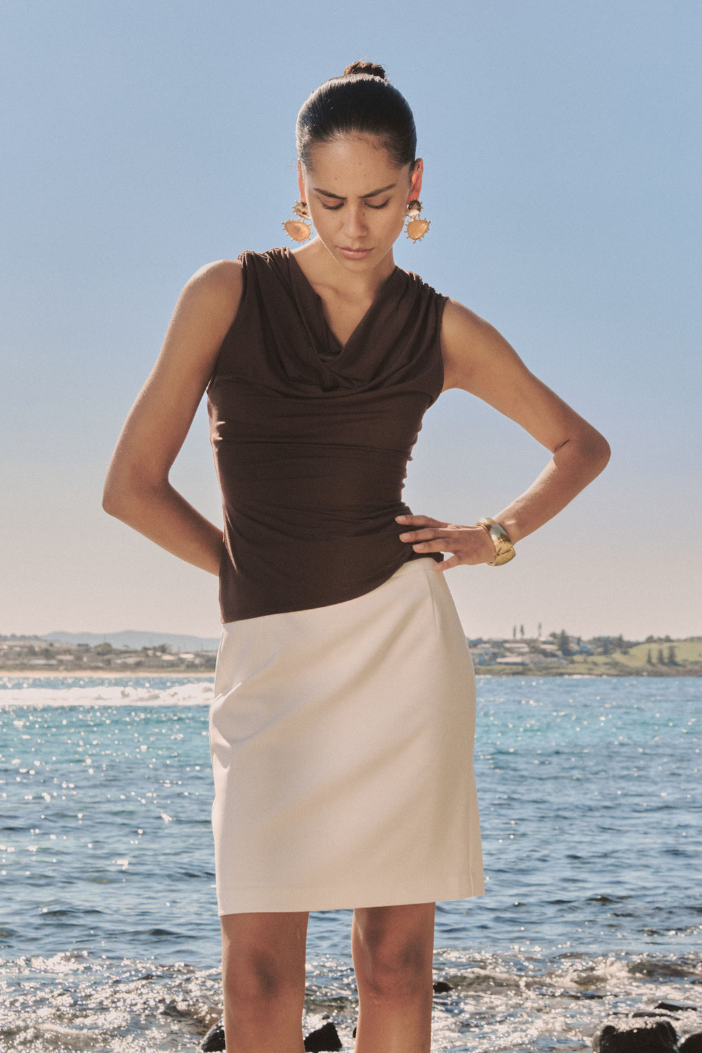 Shayna Bamboo Cowl Top in Fudge worn with a cream skirt outdoors, front view
