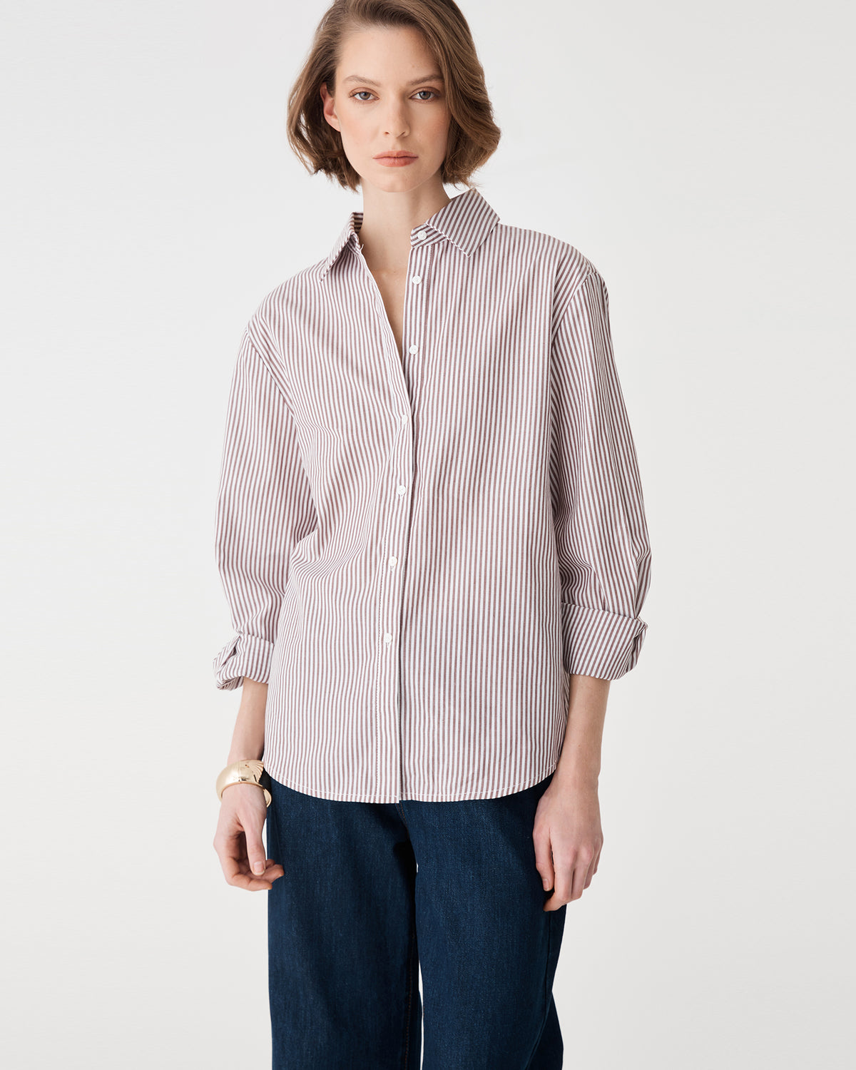 Front view of the brown stripe shirt, cropped at the hip with sleeves rolled