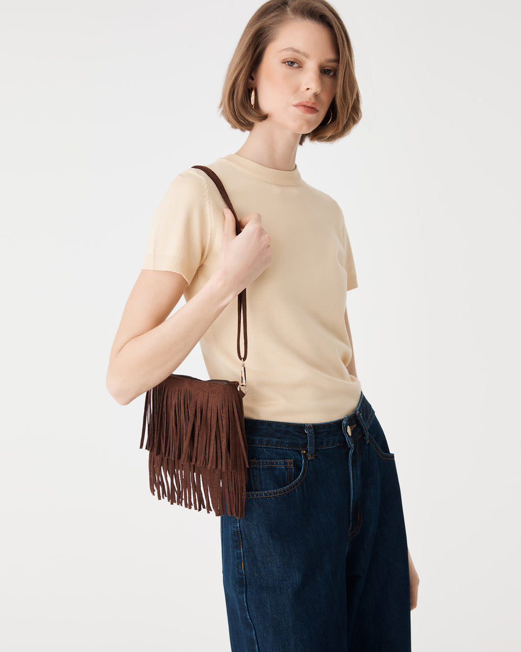Tulum Fringe Bag in Chocolate Fondant held at the front, fringe detail with cream knit top and denim